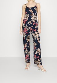 Blommig tvådelad outfit med marinblå bakgrund, rosa och röda blommönster, lättviktigt tyg och spaghettiband på toppen.