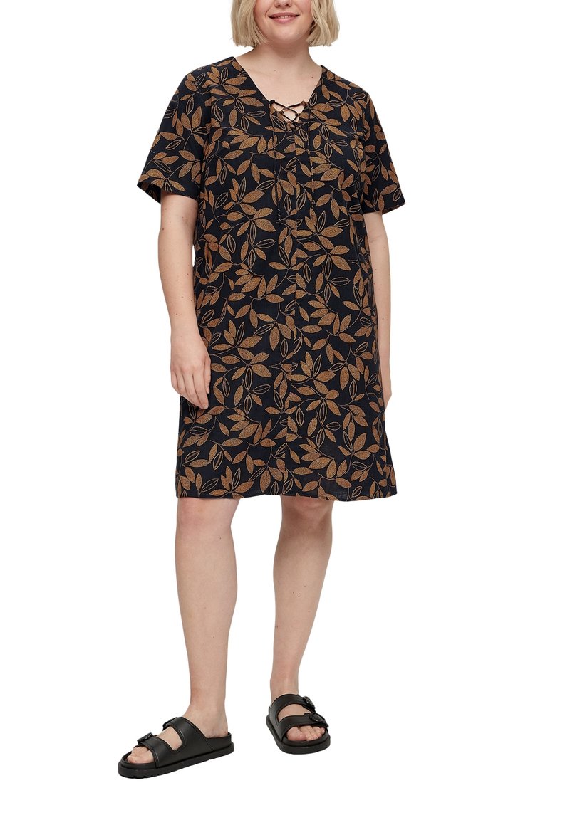 Vestido negro con patrones de hojas doradas, mangas cortas y escote con cordones, hecho de un tejido ligero. Llevado con sandalias negras.