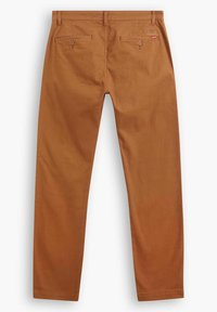 Bruna bomullshängsel med rak bendesign, med två bakfickor med knappar och en liten logotypetikett nära midjan.