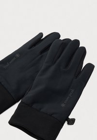 Guanti neri realizzati in un tessuto elastico, caratterizzati da un polsino aderente, una presa testurizzata e il marchio "snow peak" impresso sul retro.