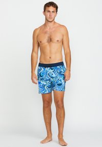 Shorts de bain bleus avec un motif tourbillonnant de bleus clairs et foncés, dotés d'une taille sombre. Le matériau semble léger et à séchage rapide.