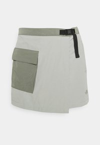 Falda gris claro con un bolsillo doblado en verde oliva, cinturón negro ajustable y textura suave, diseñada para actividades al aire libre.