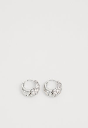 Orecchini a cerchio in argento con superficie testurizzata e un grappolo di pietre trasparenti su un lato, creando un sottile effetto luccicante.