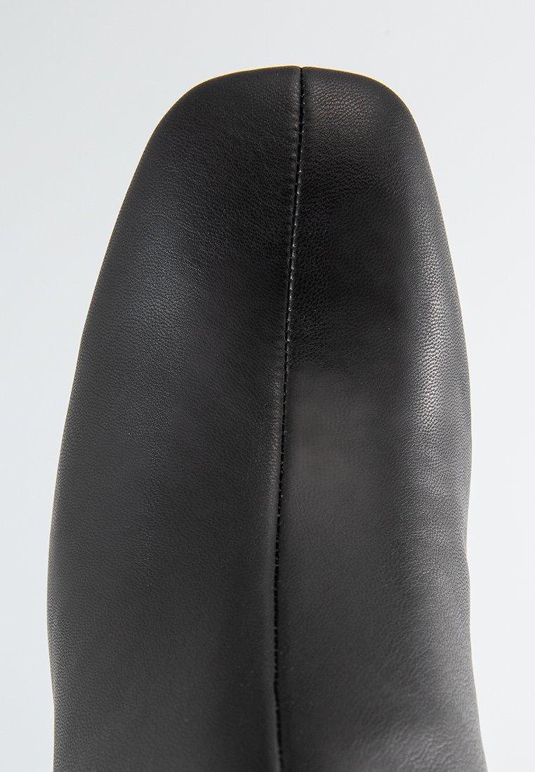 Schwarze Lederan boot mit einem eleganten Design, runder Zehenpartie und sichtbaren Nähten entlang der Naht. Glatte Textur und minimale Beschläge.