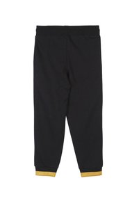 Zwarte leggings met een elastische tailleband en gele manchetjes bij de enkels. Gemaakt van soepel stof, met een naadloos achterontwerp.