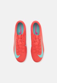 Scarpe da calcio rosse brillanti con superficie testurizzata, dotate di un logo Nike blu chiaro, lacci e una fodera interna teal.