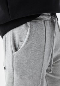 Gray sweatpants made of soft cotton blend, featuring an elastic waistband, side pockets, and subtle stitching details.