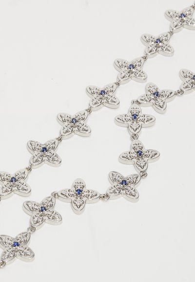 Silver necklace with repeating ornate clover-shaped links, each featuring an intricate filigree pattern and small blue gemstone center.