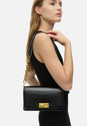 Black leather handbag with a gold-tone chain strap and rectangular clasp. Smooth texture, minimalistic design, and structured shape.