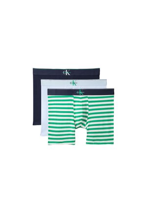 Trzy męskie bokserki ułożone w stos, kolory od przodu do tyłu: zielone i białe paski, jednolita biel, jednolity granat, każda z paskiem Calvin Klein.
