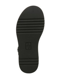 Suola di scarpa in gomma nera con scanalature orizzontali, caratterizzata da un logo impresso al centro, superficie liscia e forma della punta arrotondata.