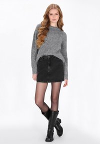 Szary sweter dzianinowy, czarna spódnica dżinsowa, przezroczyste rajstopy i czarne wysokie kozaki z klamrami. Prosty design, codzienny strój.