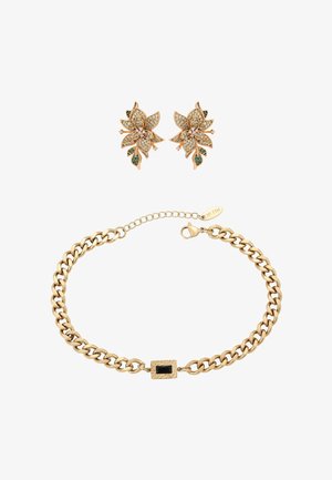 Arany virágos fülbevalók áttetsző és zöld kövekkel, vastag aranylánc karkötővel párosítva, melynek kapcsa fekete téglalap alakú kő.