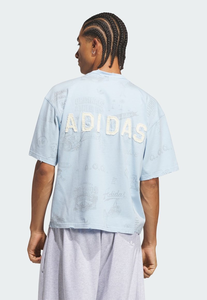 Hombre con el pelo trenzado que lleva una camiseta azul clara de Adidas con un gran logo texturizado en la espalda y pantalones cortos gris claro, de espaldas.