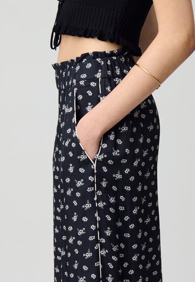 Pantalones de pierna ancha con estampado floral en tonos navy, con una cintura fruncida, bolsillos laterales y un ribete blanco que acentúa las costuras delanteras.