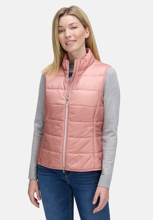 Padded vest w kolorze jasnoróżowym, z wysokim kołnierzem, zamek błyskawiczny z przodu i pikowanym wzorem. Noszony na jasno-szarym, długim rękawie.