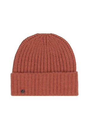 Rust-colored ribbed knit beanie with a folded cuff and a small round metal logo tag on the cuff's lower left side.