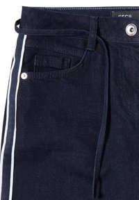 Pantalones de mezclilla azul marino con rayas blancas laterales, con bolsillo frontal, trabillas para cinturón y cierre con botón metálico. Textura suave, diseño ajustado.