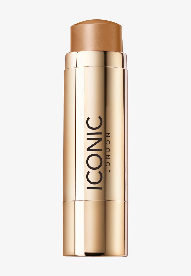 Cream foundation stick in a sleek gold tube. The top is brown, indicating medium tone, with "ICONIC LONDON" printed in bold black.