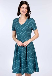 Teal Kurzarmkleid mit V-Ausschnitt, das ein weißes Kirschmuster aufweist und einen weit schwingenden Rock hat. Hergestellt aus weichem, leichtem Stoff.