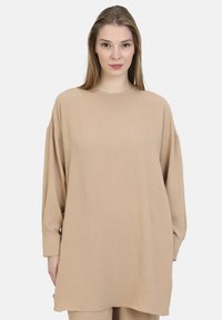 Maglione beige oversize con maniche lunghe, scollatura rotonda e tessuto morbido e testurizzato. Presenta una vestibilità rilassata e polsini ai polsi.