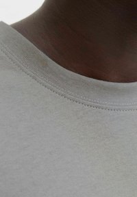 Helehall T-särk ümara kaelusega, mis on sileda tekstuuri ja õrnade õmbluste detailidega kaeluse ääres.