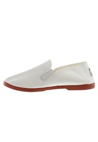 Witte canvas instapschoen met elastische zijkanten en een bruine rubberen zool. Gladde textuur, minimalistisch ontwerp en een ronde neusvorm.