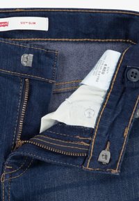 Tummansiniset Levi's 511 Slim farkut, joissa on vetoketjulla varustettu etumalli, metallinen nappisuljenta, ommellut yksityiskohdat ja hoito-ohjetarra vyötärönauhan sisäpuolella.