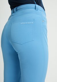 Ljusblå stretchbyxor med en figurnära design, som har en bakficka och prägling med logotyp. Slät tyg och sömlöst midjeband.