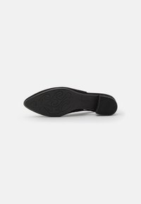 Scarpa nera con tacco alto e punta affusolata, dotata di una suola in gomma textured con un motivo a spirale. Il materiale superiore sembra liscio e sintetico.
