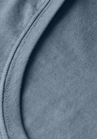 Modrá tkanina s hladkou strukturou, s zakřiveným švem a kontrastním stehem, což vytváří vrstvený vzhled.