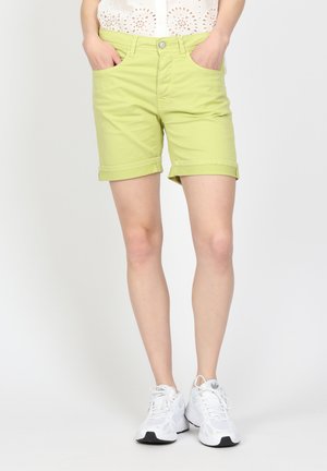 Light green cotton shorts with rolled cuffs, front pockets, and a front button closure, paired with white athletic shoes.