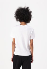 Witte katoenen t-shirt met een ronde hals, korte mouwen en een relaxte pasvorm, gezien vanaf de achterkant. Gladde textuur, geen zichtbare patronen.