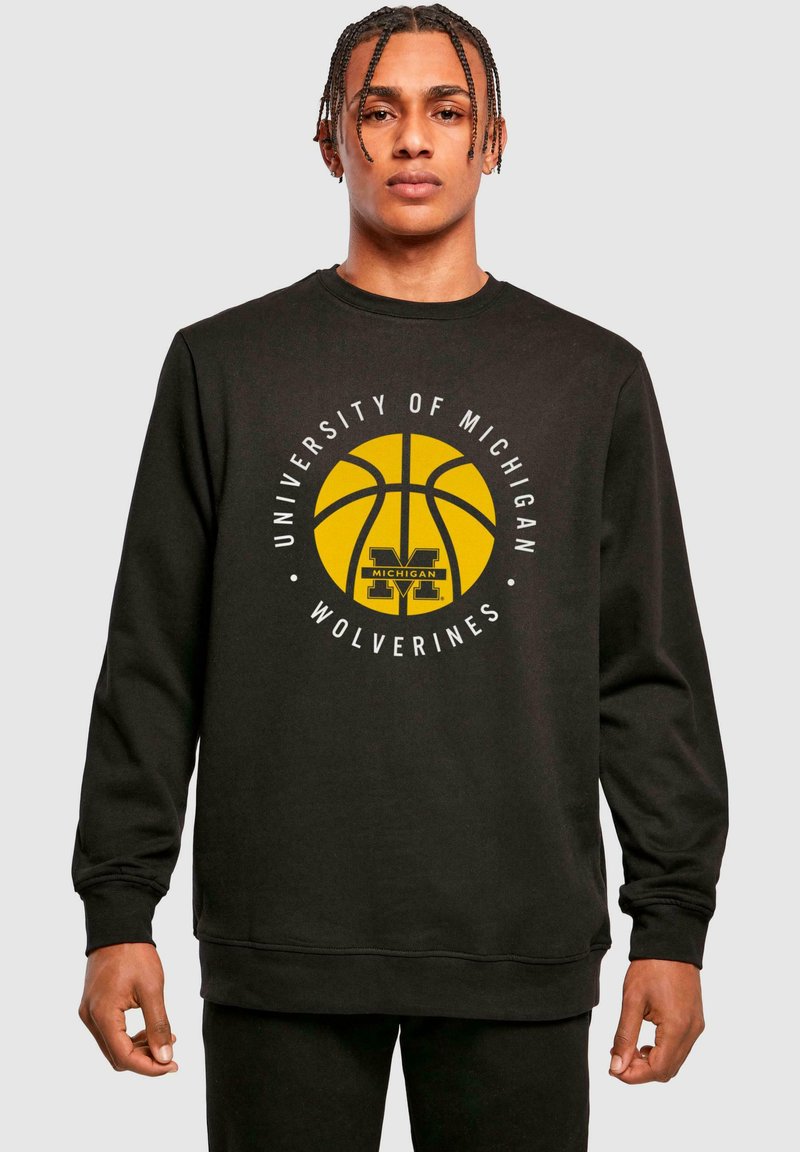 Czarna bluza z białą grafiką przedstawiającą koszykówkę oraz napisem "University of Michigan Wolverines" w kolorze żółtym i czarnym.