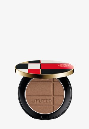 Poudre bronzante compacte embossée du texte "Shiseido", contenue dans un boîtier rond noir avec un couvercle bordé d'or décoré d'un motif géométrique rouge, noir et blanc.