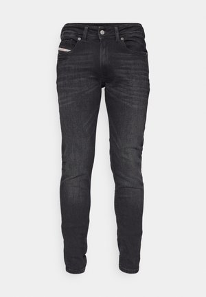 Jean en denim noir à coupe ajustée, avec poches avant standard et fermeture à bouton en métal. Présenté sur un fond blanc.