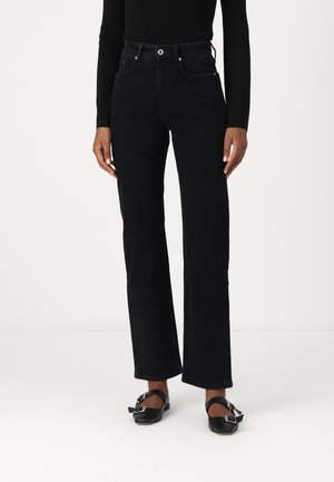 Jeans de mezclilla negros de talle alto, con corte recto, cinco bolsillos, detalles de costura y herrajes en tono plateado. Pies adornados con zapatos planos negros.