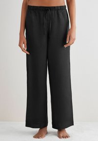 Svarta, löst sittande linbyxor med dragsko i midjan och vida ben, med en slät yta och utan synliga mönster eller detaljer.