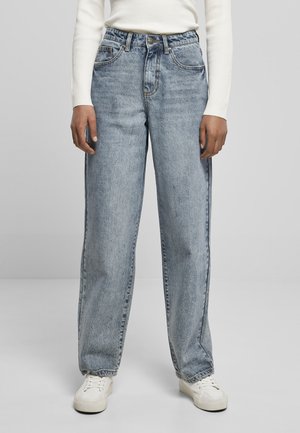 Ljusblå denim vid byxor med midjeband och framfickor. Bärs med vita sneakers och en ribbad långärmad topp.