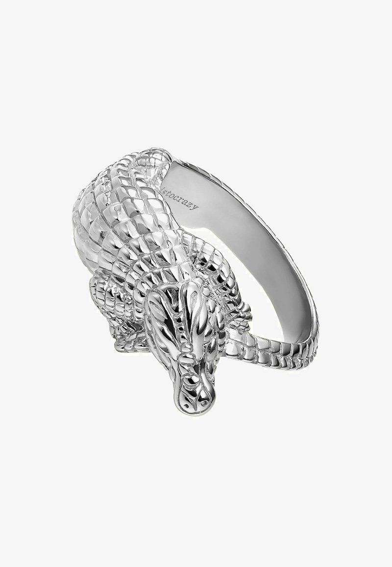 Anillo en forma de dragón plateado con intrincadas escamas, detalles y una banda interior lisa con un logo sutil. El diseño es tridimensional.