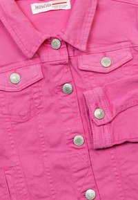 Růžová džínová bunda se stříbrnými patentkami, náprsními kapsami a klasickým límcem. Texturovaná tkanina s viditelnými švy.