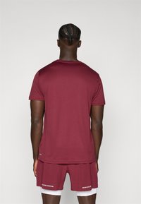 Bordeauxkleurig sport T-shirt met korte mouwen en een ronde hals, gecombineerd met bijpassende shorts met een witte opdruk aan de zoom.