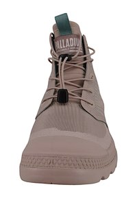 Sneaker alta beige con tomaia in tessuto testurizzato, lacci elastici, linguetta verde e soletta in gomma pattern.