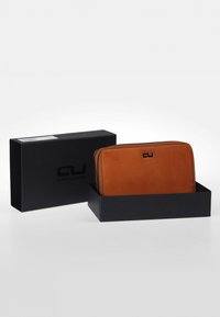 Brown leather wallet with a smooth texture, zip closure, and black accents; displayed in a black box with logo.
