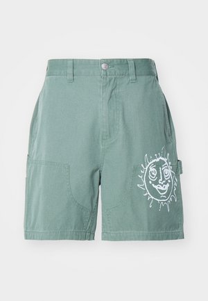 Green cotton shorts with a relaxed fit, featuring two front pockets and a white sun graphic on the right leg. Plain hemline, no patterns.