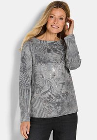 Grijze langemouwenshirt van een zachte stof met een bladerenpatroon en decoratieve pailletten. Ronde hals en aansluitende mouwen, gecombineerd met donkere jeans.