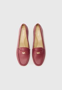 Burgundy leather loafers feature a rounded toe, stitching details, and gold "MK" hardware on the front. Cushioned insole and smooth texture.