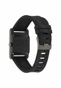 Bracelet de montre en caoutchouc noir avec un boîtier en métal rectangulaire. Comprend un fermoir rond, un logo gravé et plusieurs trous pour un ajustement réglable.