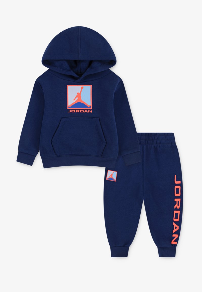 Marineblå hættejakke med frontlomme, orange Jordan-logo på brystet, matchende bukser med logo på benet. Fremstillet af blødt, behageligt stof.