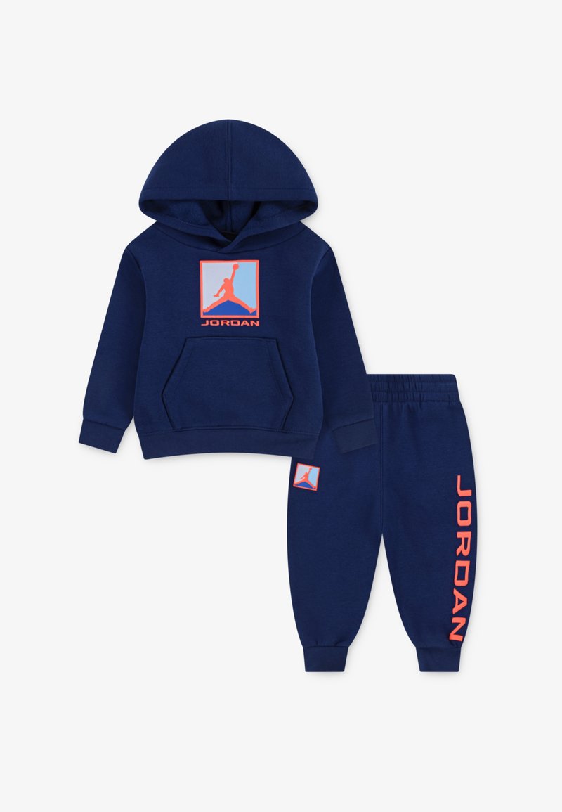 Marineblå hættejakke med frontlomme, orange Jordan-logo på brystet, matchende bukser med logo på benet. Fremstillet af blødt, behageligt stof.